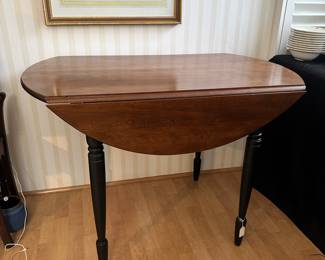 R20 - $125 - Round Wood Drop Leaf Dining Table. Chairs not included. The table is in great condition! With natural wood finish on top and black painted legs. Measures 42" round and 26"W when dropped.