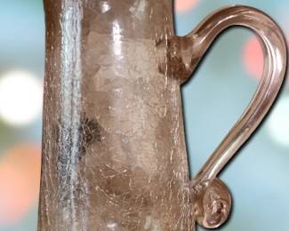 Pink-tinted glass pitcher with a distinct crackle finish. The pontil mark on the bottom indicates it was hand-blown. Crackle glass was popular in the 1920s and 1930s.