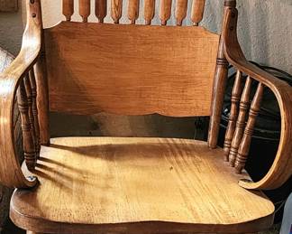 Antique wood sturdy rocking chair, pressed-back style. The wood has a noticeable grain and a clear finish that highlights the wood's inherent beauty.