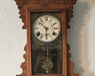 E.N. Welch "Sylvia" shelf clock. The glass panel features etched designs. The decorative brass pendulum bob has intricate detailing.