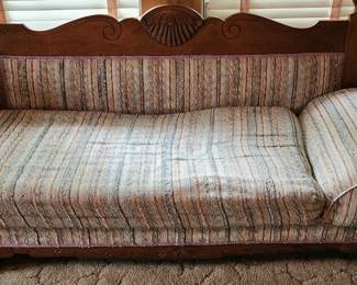 Antique fainting couch, The wood is oak and features carved details, particularly on the backrest, which has a shell-like or fan motif in the center and elegant scrolling on either side.
