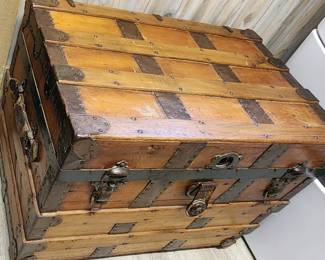 Antique steamer trunk. It has a wooden frame with metal bands and corners, and it features a latch and a handle.