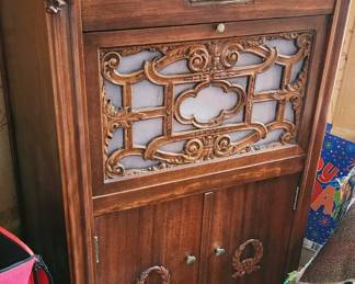 Antique wooden phonograph, possibly a Paramount phonograph, in well preserved condition.
Top section: hinged lid to access turn table and winding mechanism.
Upper cabinet: decorative panel to house controls.
Middle section: ornate grill work allows sound to project.
Lower cabinet: stores records.