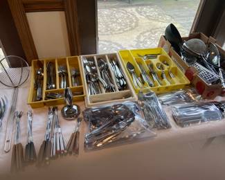 Several sets of flatware and numerous flats of kitchen utensils.