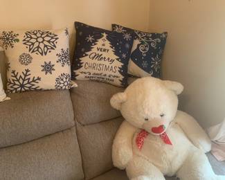 Oversized, teddy bear and Christmas cushions on a gray electric recliner