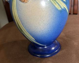 Roseville Pottery Blue Pinecone Vase, a popular pattern introduced in 1935 by Frank Ferrell.
Here's some information about it:
Design:
The vase features a molded design with pine cones and curved pine needles attached to bark-textured branches against a smooth background. It typically has branch-like handles.
Colors:
The Pine Cone pattern was produced in blue, brown, green, and pink. Blue is highly sought after, with pink being the rarest and most expensive.
Markings:
Early pieces were marked with foil labels or hand-written shape numbers. Later pieces had die-impressed or raised Roseville script marks, shape numbers, and sizes.
Production:
Roseville Pottery was established in Roseville, Ohio, in 1890, and ceased operations in 1954. The Pine Cone line was one of their most popular and successful designs.
Collectibility:
Roseville pottery is highly valued by collectors for its historical significance, artistic appeal, and nature-inspired designs.
$500 obo