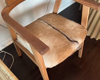 Style: Mid-Century Modern / Scandinavian
Material: walnut frame
Seat: Natural goat or cowhide upholstery, possibly African springbok
Backrest: Curved wood plank, ergonomically carved
Arms: Integrated with the frame, smooth and minimal
Light natural variation in the hide