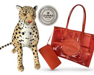 Plush cheetah stands 22” tall alongside roomy orange-red tote w/pouch by cruelty-free, PETA-approved fashion brand GUNAS NEW YORK; bag has embossed brand logo:  Love Animals~Love Planet~Love People; bag dimensions approximately 17-3/8"L x 13-3/8"H x 4-3/4"D; pouch 10"W x 6”H