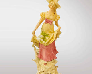 Bisque figurine of a lady in a pink and yellow dress.