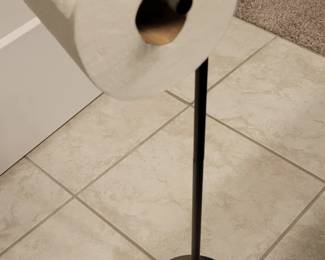 Freestanding metal toilet paper holder.