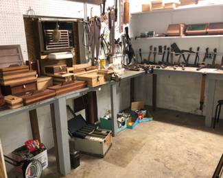 Workshop displays multiple antique tools, hand crafted wooden boxes, jewelry boxes, display cases.  Axes, hatchets, vintage hand tools.  