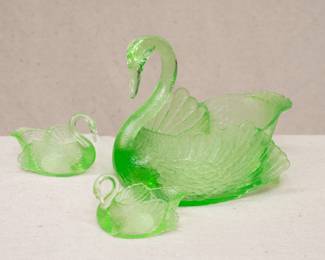 A vintage Cambridge vaseline glass or green uranium glass swan punch bowl, with two small matching swan shape cups. The cups marked to the base with the letter "C" in a triangle; the set dates to the 1930s.
