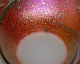 Closeup of the Charles Lotton Cypriot Lava art glass vase. Signed and dated "1991". Iridescent gather over dark red orange textured ground. Pinched rim.