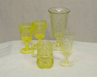 A pair of L G Wright Glass Wildflower vaseline glass stemmed glasses, an EAPG 1890's Bryce Bros Vaseline Diamond Quilted uranium glass stemmed vase and smaller goblet, and an EAPG vaseline glass star dot quilt pattern creamer or syrup jug.