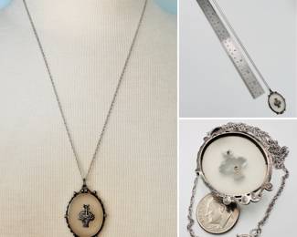 Sterling silver necklace of a delicate chain holding a frosted glass oval in a silver and marcasite frame, the glass decorated with a silver and marcasite basket of flowers. Both the pendant and chain are marked sterling.