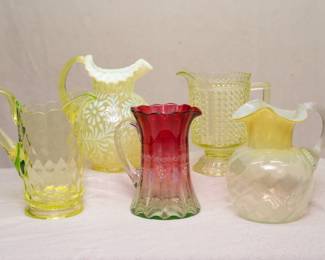Vintage and antique uranium glass or vaseline glass pitchers, including a Fenton glass Daisy and Fern pattern pitcher, a Rubina Verde glass pitcher with enamel and gilt decoration, a hobnail pattern pitcher and a Fenton pitcher with flared rim and applied clear handle
