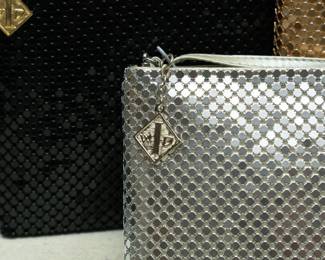 Closeup of Three 1970s vintage Whiting and Davis International metallic mesh zip top clutch bags, in black, silver, and gold