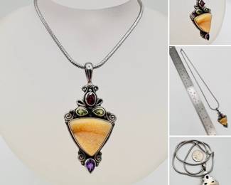 A sterling silver pendant necklace with faceted garnet, amethyst, and peridot accenting a central natural agate stone