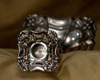 Closeup of the base from the matched set of four antique English sterling silver candlestick holders, stamped with hallmarks for sterling silver, London, and silversmith Lionel Alfred Crichton.