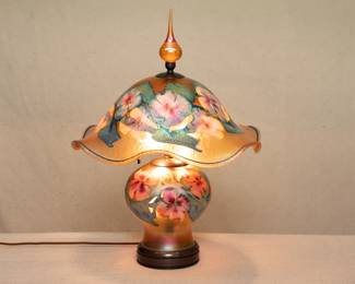 Here's how it glows when lit — the breathtaking hand made art glass lamp by American art glass master Charles Lotton (1935-2021), Illinois. This lamp shows Lotton's "Multi Flora" design, iridescent gold ground with a beautiful flower blossoms and leaves, and with original finial.