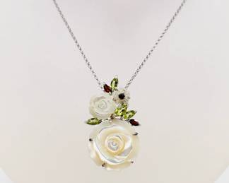 Another view of the sterling silver necklace with carved floral form mother of pearl pendant accented with garnet and peridot