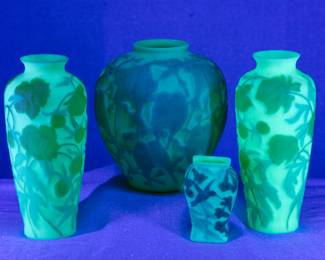 Seen under blacklight: Vintage Phoenix / Consolidated art glass, satin custard uranium glass, including a pair of yellow chrysanthemum vases, a blue lovebirds or parakeets design ginger jar shape vase, and a smaller hummingbird design vase.