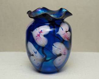 An original hand blown art glass by John Lotton, in rich blue cased glass with pink and white heart shaped flowers and dark vines, iridized flared rim. Signed John Lotton 1991.