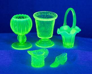 Seen under blacklight: EAPG vaseline glass - Antique Northwood opalescent vaseline uranium glass ring pedestal beaded panel rose bowl, a small clear pedestal foot uranium glass vase with panels with stork in water scene and coin dot flared lip, a small clear to opalescent vaseline glass ruffled rim basket, a top hat shape uranium glass quilted pattern toothpick holder, and a wee uranium glass patterned lady's shoe