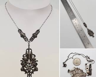 An Art Deco era sterling silver and marcasite flower basket pendant on a decorative chain from the Art Deco era. This has accent floral bars on either side of the pendant. Stamped sterling on the back.
