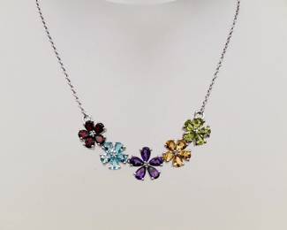 A delicate sterling silver necklace with five flower shapes of garnet, topaz, amethyst, citrine, and likely peridot