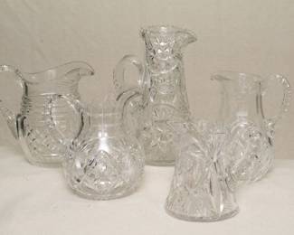 Five different cut glass pitchers and creamers