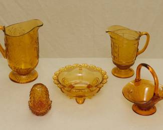 Amber art glass – a beautiful antique EAPG amber glass milk pitcher in the Hummingbird pattern made by the Co-Operative Glass Company circa 1890, an antique 19th century Bryce Brothers Wreath or Willow Oak EAPG amber glass water pitcher, a vintage 1960s Fenton Art Glass hobnail fairy light lamp 2 piece votive candle holder; a rare Indiana Tumbler & Goblet Co. Dewey aka Flower Flange EAPG amber glass bowl circa 1898, and a lovely vintage a golden amber basket made for Tiara by Indiana Glass Company in a pattern called Sandwich