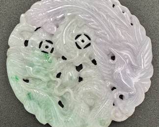 A Chinese carved dragon and phoenix bird on a pale green to lavender jade rondel