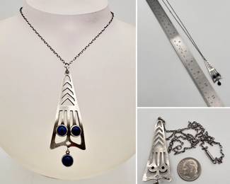 A dynamic and beautiful sterling silver Art Deco pendant in a stylized arrowhead shape, set with three round blue cabochon stones, on a linked chain. Marked sterling.