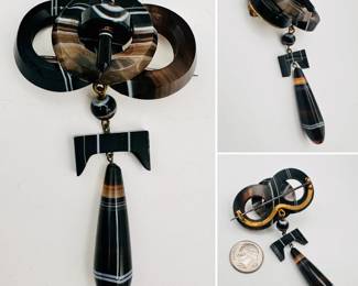 Antique Scottish pebble jewelry brooch of black agate with white and brown bands, carved in 4 rings and one rod shape forming a buck, with large pendant teardrop bead. Sterling silver pin and frame to the back, unmarked; late 19th century.
