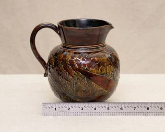 A Royal Doulton Lambeth stoneware pottery jug with a leaf pattern in a brown and greenish glaze, circa 1891-1934