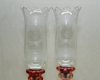 Closeup of the magnificent pair of Baccarat Rose Tiente candlesticks' matching blown clear glass hurricane shades engraved with diamond pattern bands and beribboned floral sprays, and an Arabic inscription.