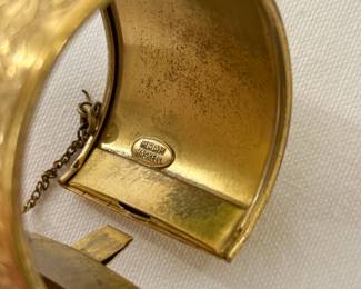 Closeup of the rare vintage Miriam Haskell wide cuff bracelet, gold tone with intricate floral pattern, safety chain