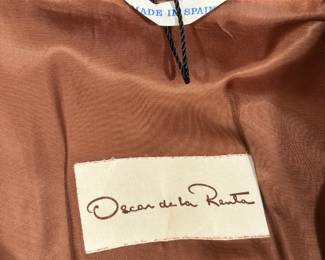 Closeup of the vintage 1970s Oscar de la Renta cognac suede coat, lined, with leather blanket stitching throughout, button closure. Made in Spain, likely a size Medium.