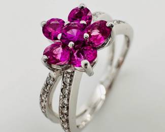 Closeup of the 18k white gold split band ring, with pavé set diamonds in the bands and a central pink gemstone flower form 
