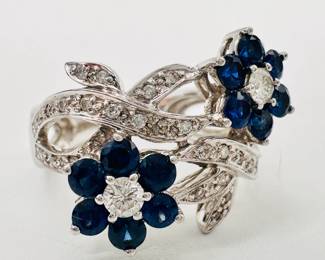 Closeup of the lovely 18k white gold diamonds and sapphire ring, sapphires set in flower form encircled by diamond ribbons
