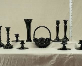 A collection of black and black amethyst glass candlesticks, handled basket, and vase