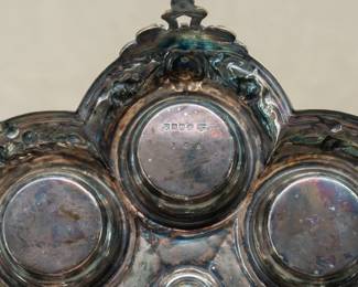Closeup of the English silver plated cruet stand with three cut glass cruets with original stoppers, matching salt and pepper shakers, and mustard pot. 