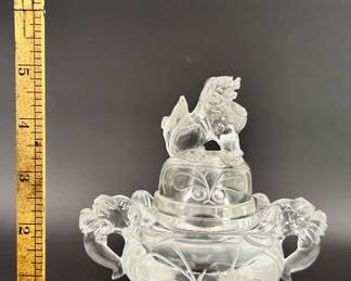 A Chinese carved rock crystal censer and cover, early 20th century, of compressed globular form, resting on three short paw-shaped feet, the lid surmounted with a seated mythical beast, shoulders are flanked by mythical beast mask handles. Both the lid and body are carved with taotie mask designs.