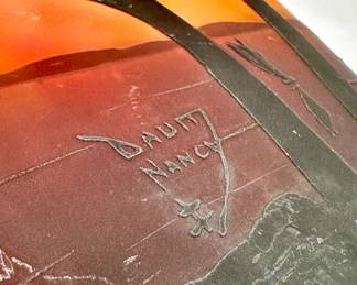 Closeup of signature on the Daum Nancy cameo glass vase decorated with sailboats on a lake seen through trees, in purple/black on an orange and yellow ground, acid etched, signed in cameo 'Daum Nancy' with the Croix de Lorraine mark