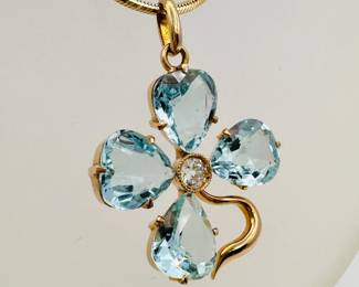 Closeup of 14k yellow gold diamond and aquamarine flower (or four leaf clover) pendant necklace