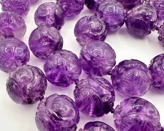 Closeup of the amethyst carved beads and 14k yellow gold clasp necklace, the beads carved with the Chinese "longevity" symbol