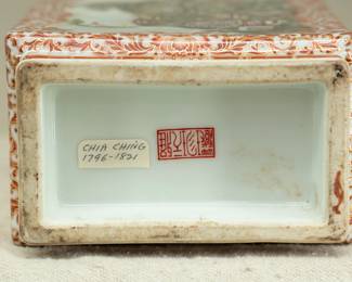 Closeup view of the base of the Chinese rectangular vase dating from the 1950s with wooden stand. Vase features a coral red lotus and flower tracery ground and 2 famille rose landscape scenes on the front and back. The bottom of the vase has a 4-character mark. 