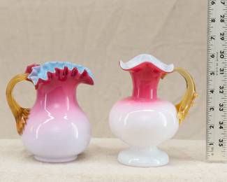American art glass: Two Hobbs, Brockunier peachblow art glass pitchers, late 19th century. The first is cased blue and white glass, the peach blow coloration shading from bright rose to pale pink, with a ruffled crimped rim, and applied ribbed amber glass handle (see another of this one in the Chrysler Museum collection!) The second is cased glass with compressed globe body on raised pedestal foot, the peachblow shading from vivid pink at the flared rim to palest pink at the shoulder; with applied amber glass thorn handle.