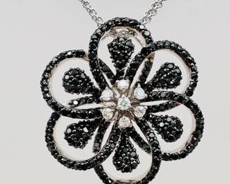 Closeup of the 18k white gold Bailey Banks & Biddle black and white diamond flower pendant necklace in original box